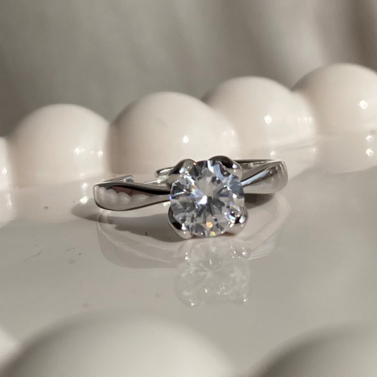 Diamond ring on a white marble surface with light reflections
